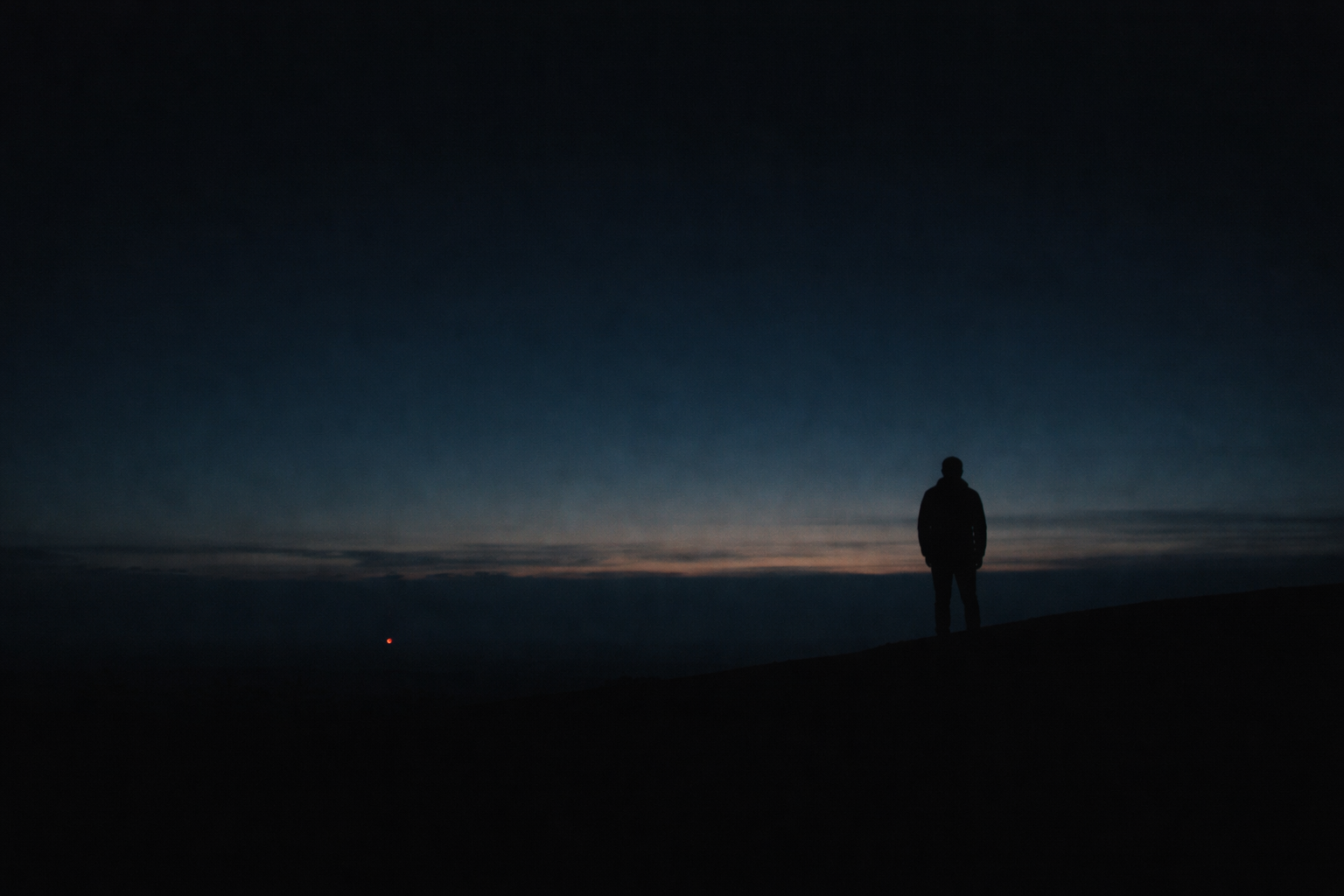 A lone figure on a ridge at blue hour. Patience, not performance.